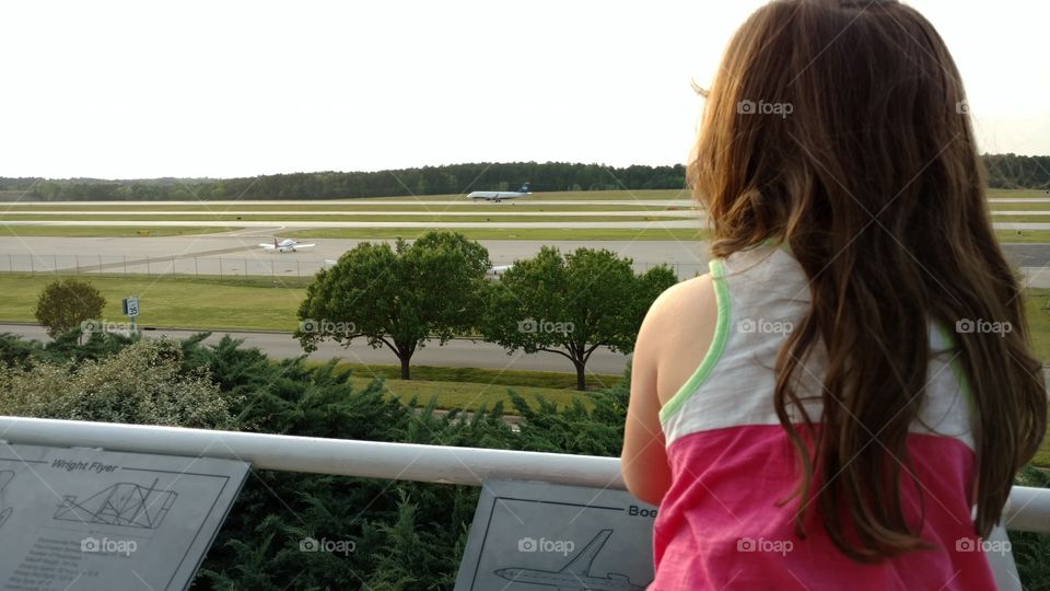 Little girl watching an airplane take off