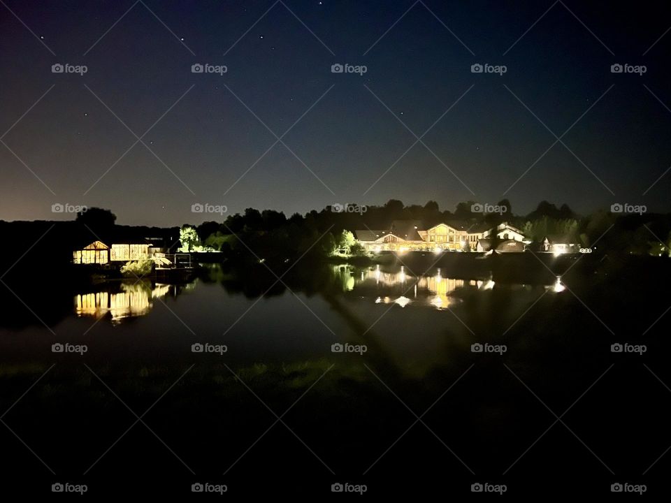 Cozy wooden houses with luminous windows on the lake shore