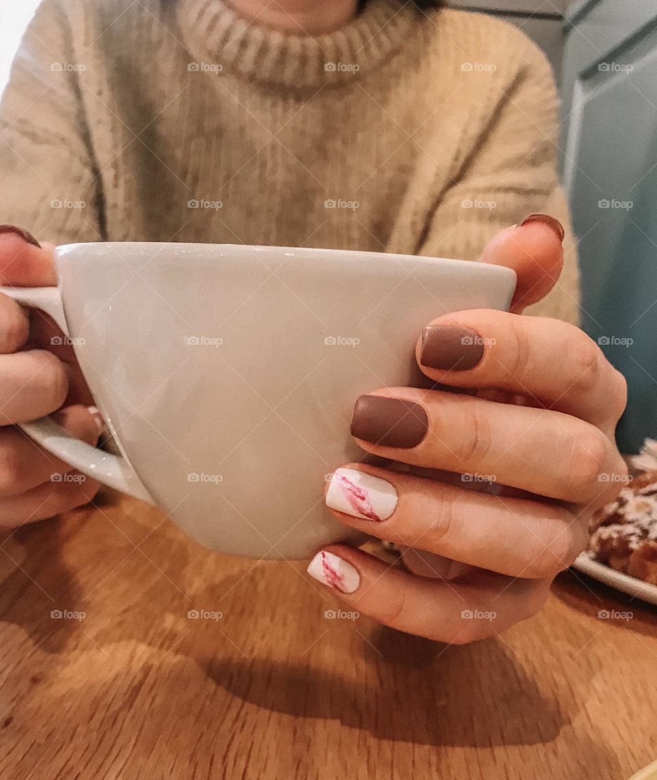 Woman manicure. Hands holding coffee tea cup. Female beautiful nails. 