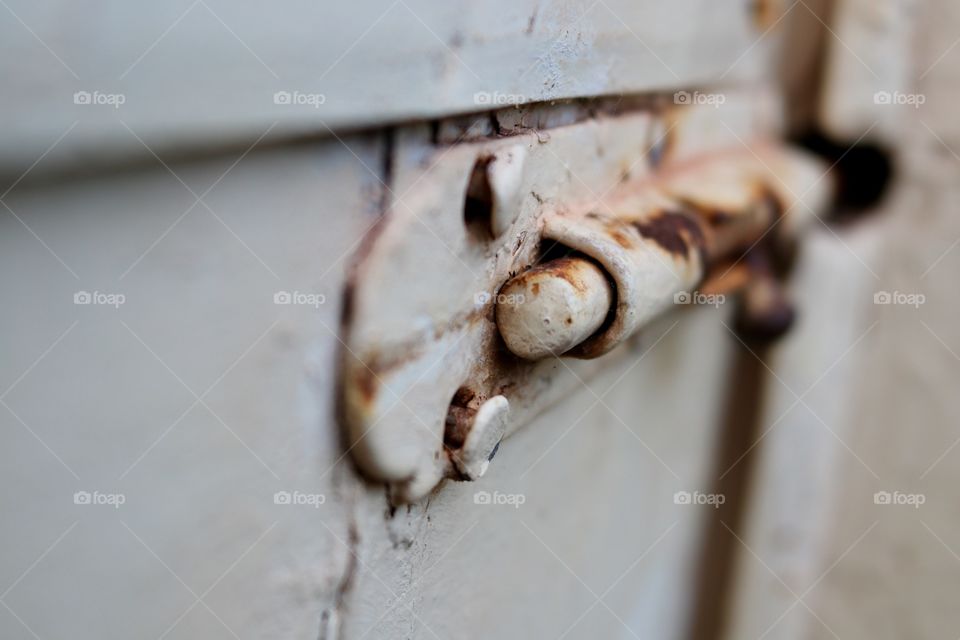 Rusted latch on antique painted outside door 