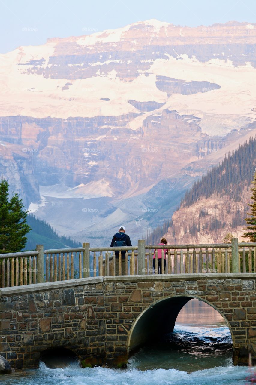 People stopped on old stone bridge to view beautiful Lake Louise in Canada's Rocky Mountains 