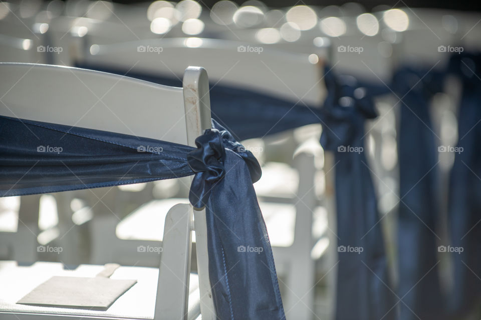 White wedding reception chairs with blue bows and ribbons