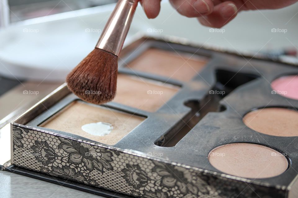 Makeup set with brush in lady's hand