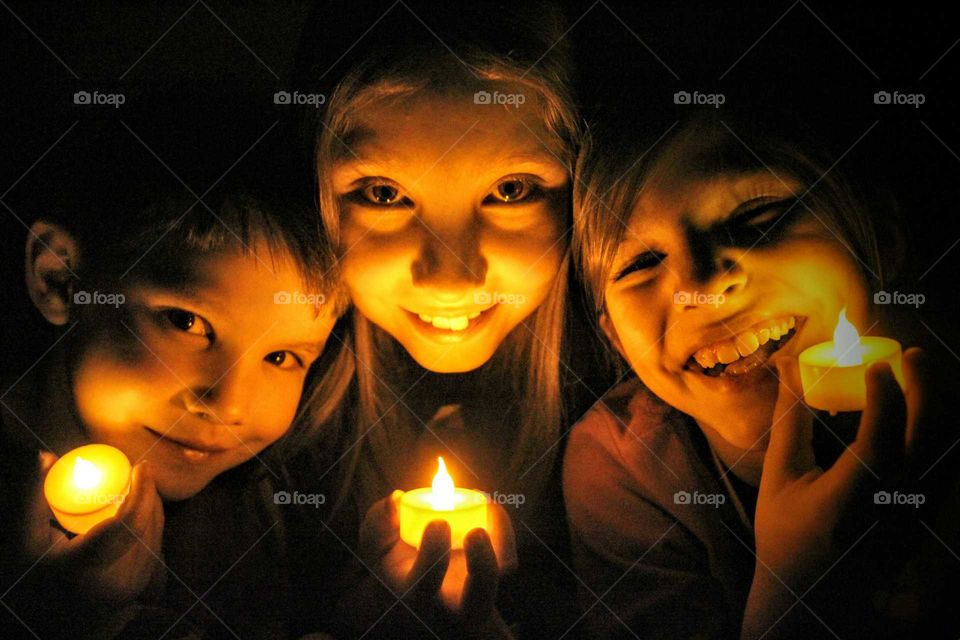 Brothers and sister holding illuminated candles at night