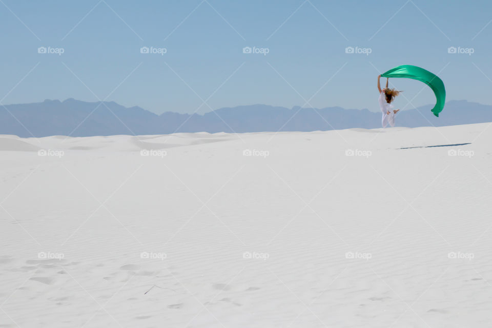 Woman jumping with scarf at beach