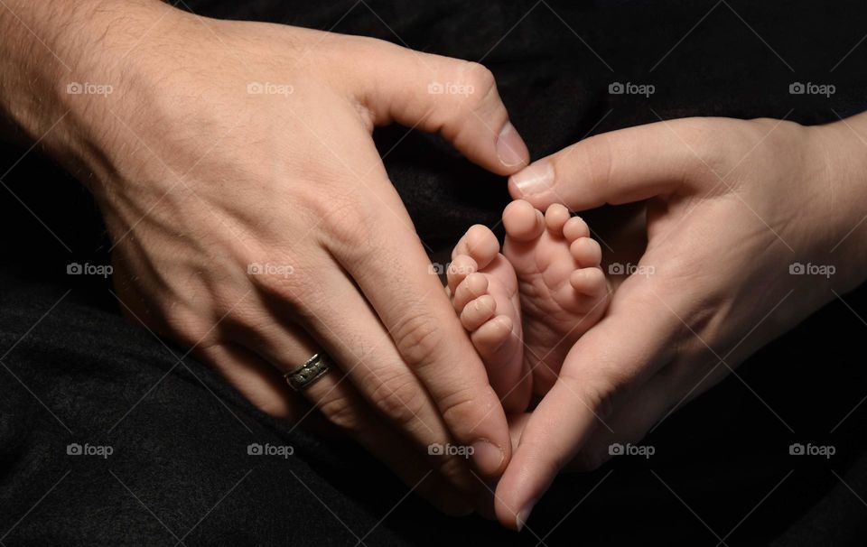 Husband and wife holding their infants feet