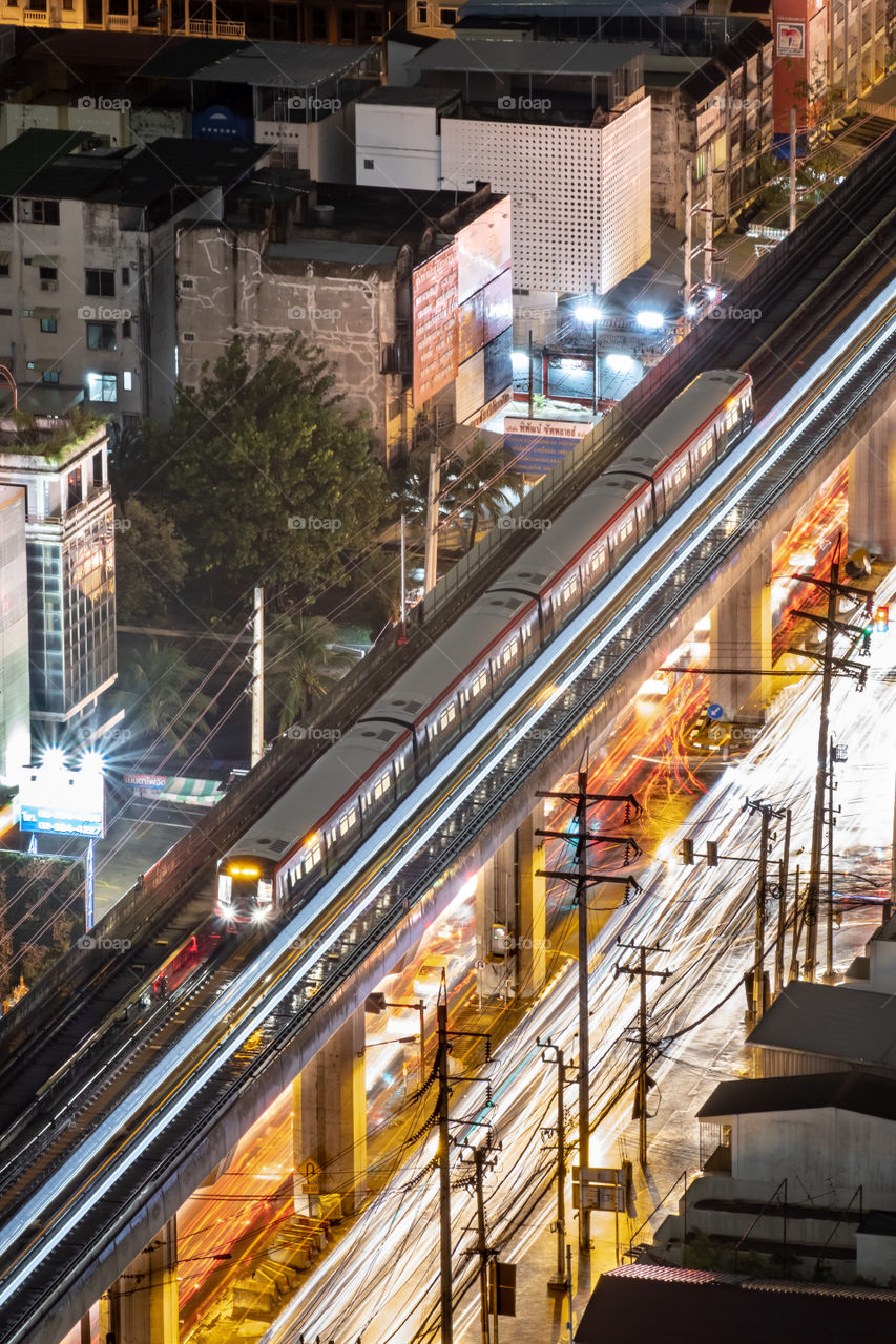 BTS train above beautiful line of vehicle light and reflect on waterlogging after heavy rains in Bangkok Thailand