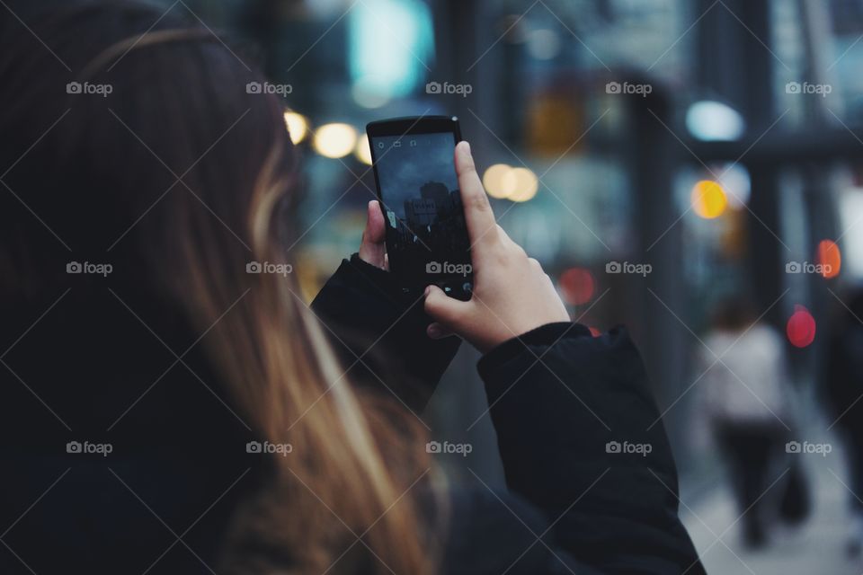 A young woman taking city pictures on her phone