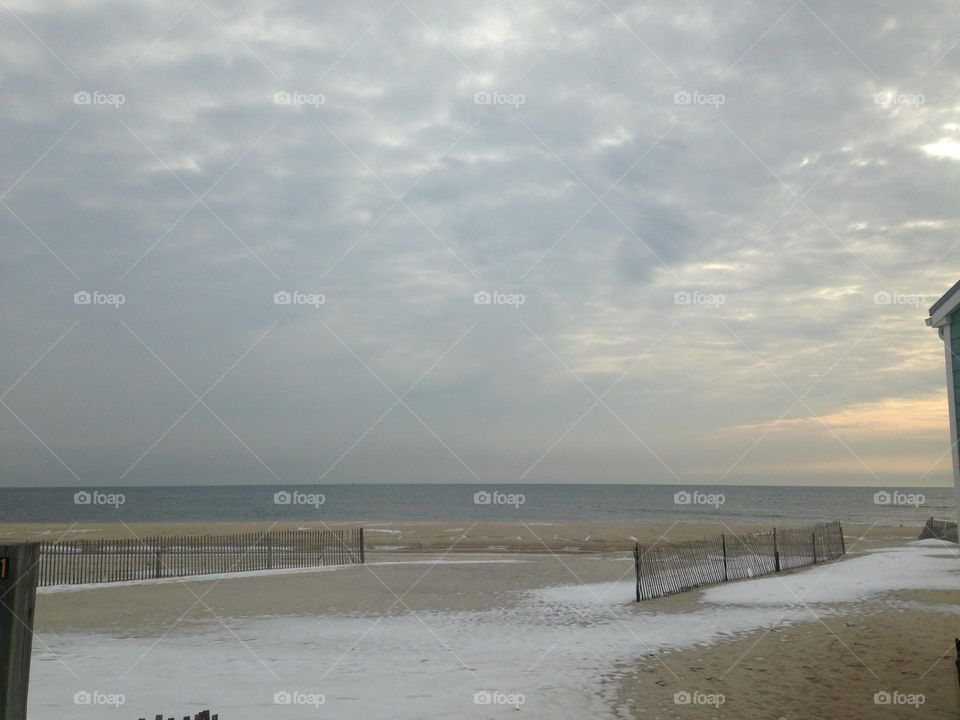 The beach in winter. Contrary to popular belief, the beach is beautiful all year long. In this shot, traces of snow are still on the sand after a storm in Point Pleasant Beach, NJ. The sky above the ocean is filled with clouds with just enough color.