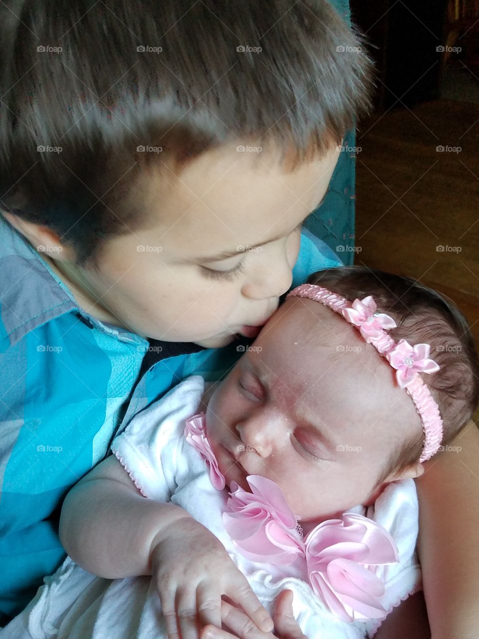 Close-up of a brother kissing little sister on her forehead