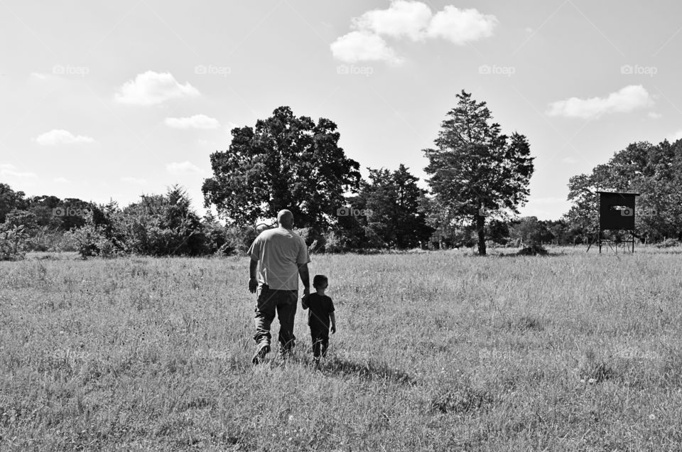 Black and white picture of my husband and grandson walking in a hay field in the country 