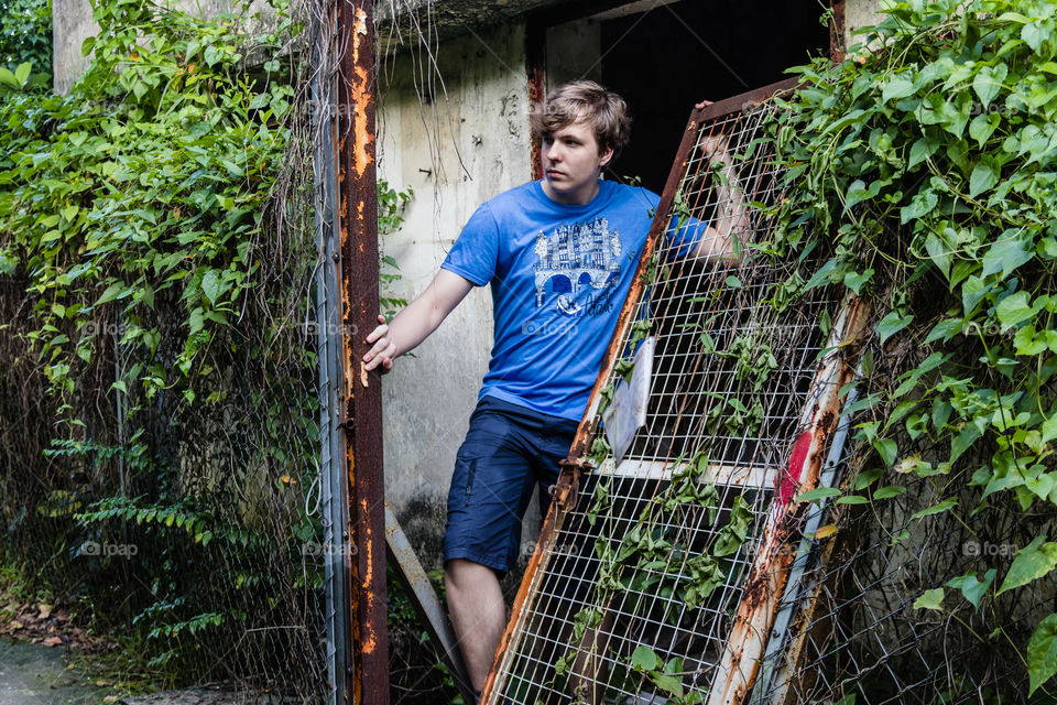 A handsome teenager standing at the entrance to the abandoned house