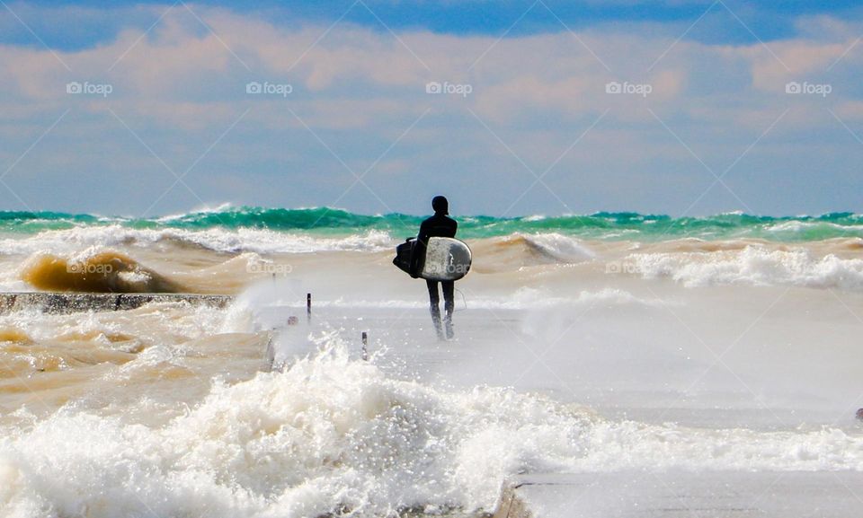 Lone surfer getting ready to jump into rough waters.