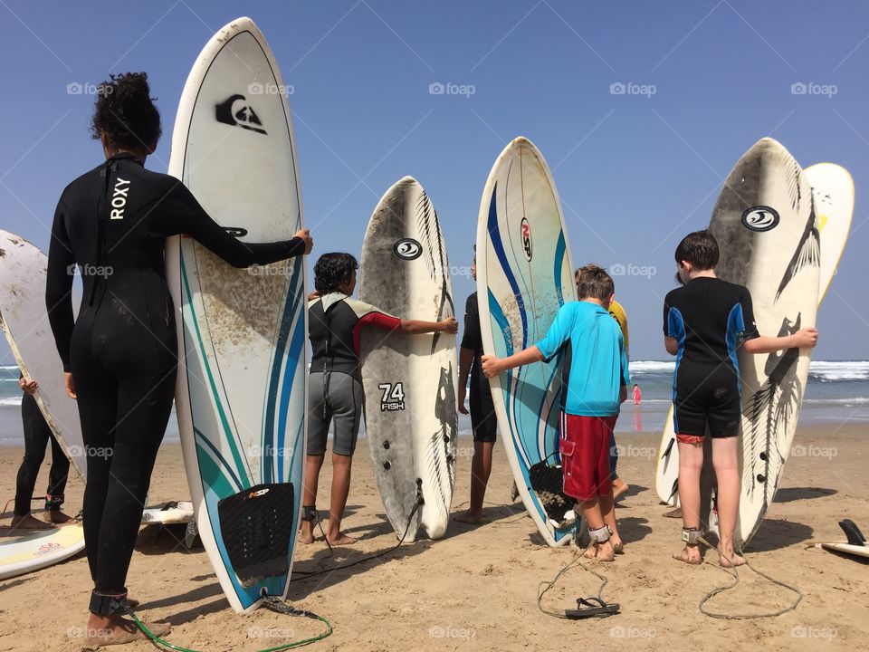 A group of youngsters waits to enter the water during a surf lesson..
