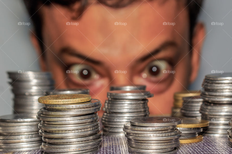 A rich greedy elderly man looks at coins. The collector looks at his wealth. An elderly man staring at metal money on the floor. 