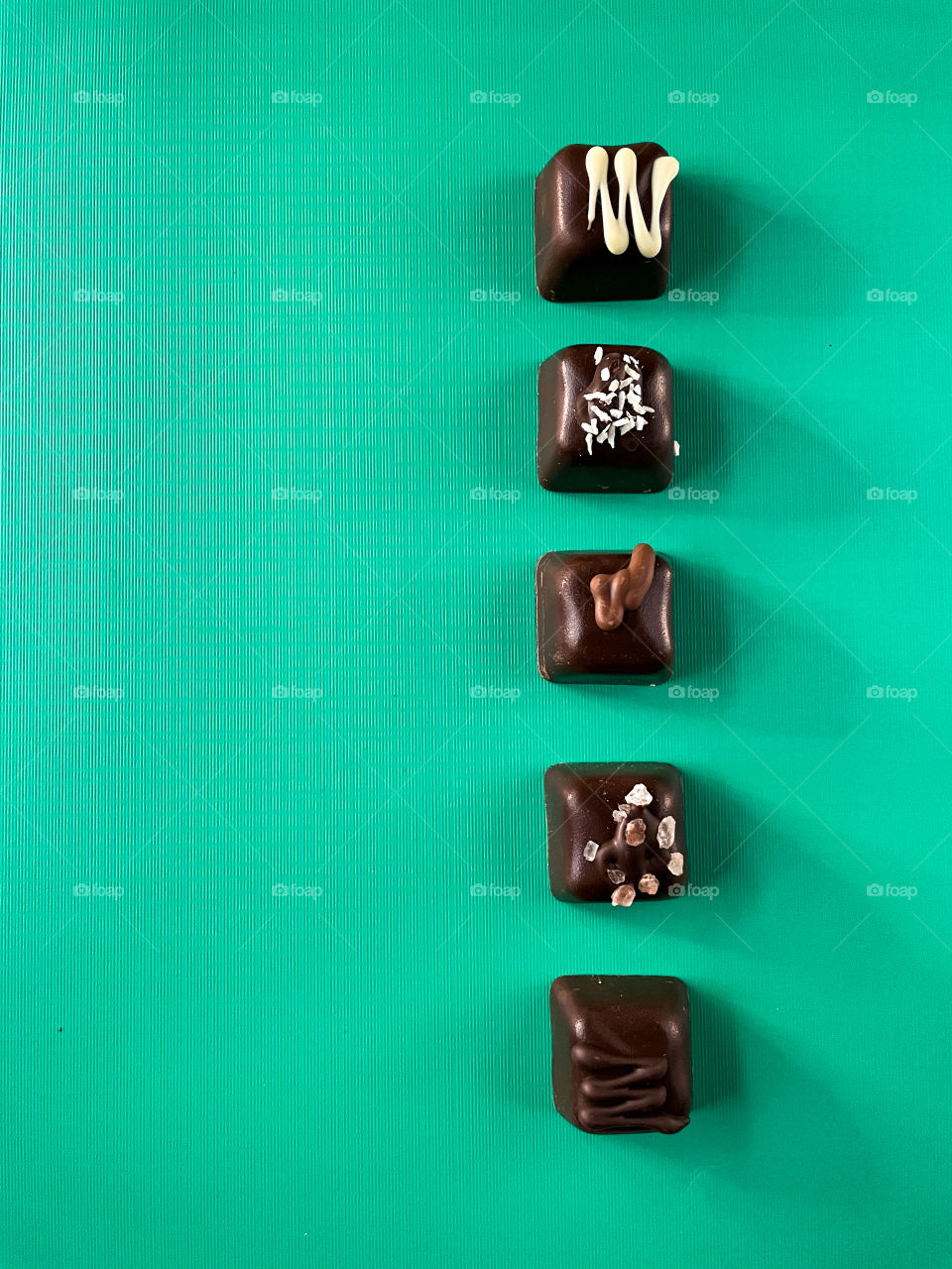 Flatlay of fancy chocolates lined up on an aqua background 