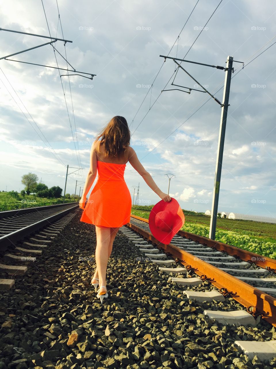 Rear view of woman walking on railroad holding hat