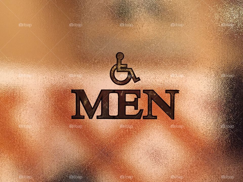 Men's room. Men's room sign with wheelchair accessible on frosted glass door.