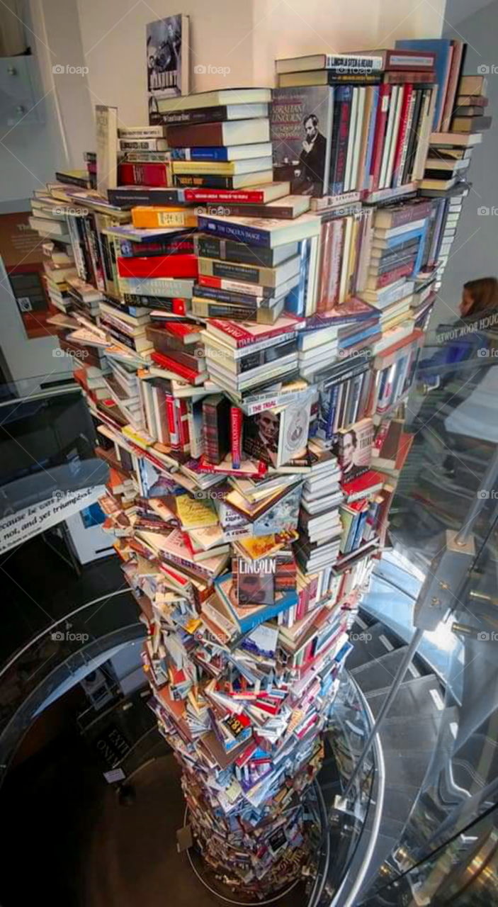 Tower of books with spiral staircase surrounding it. circular book stacking. Read.