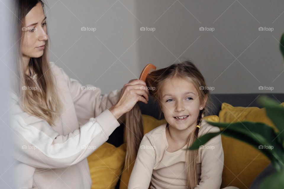 Mother brushing hair her daughter 