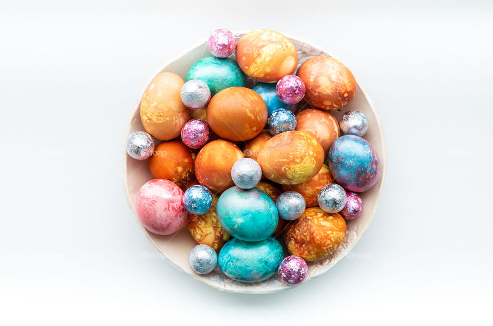 Top view of colourful dyed Easter eggs on a white background.