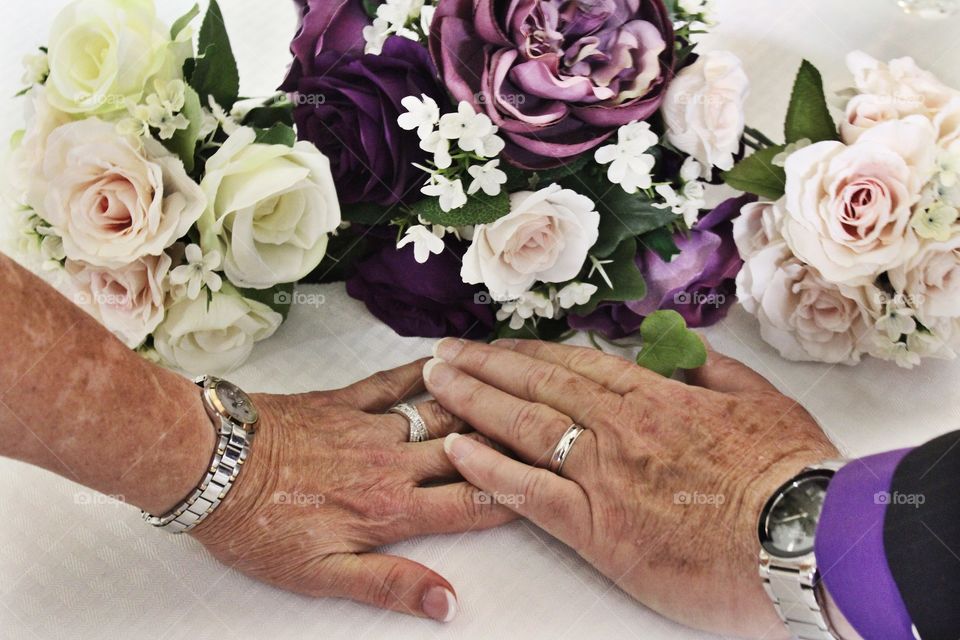Senior marriage with hands, rings and flowers. 