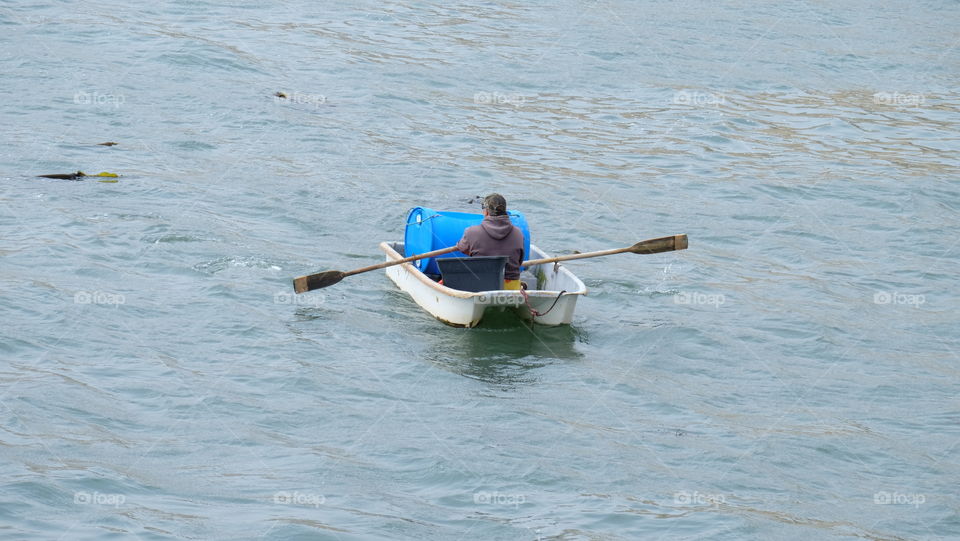 Working on the harbour, fisherman travels by row boat.