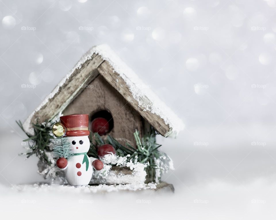 Wooden snowman outside a snow covered wooden hut
