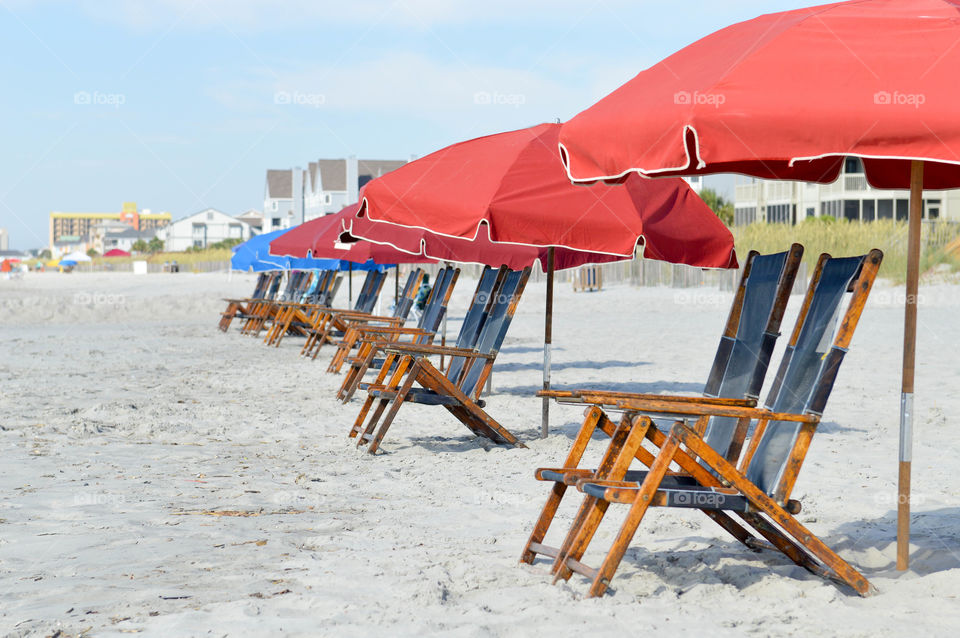 Row of lounge chairs and umbrellas set up on the beach with no people