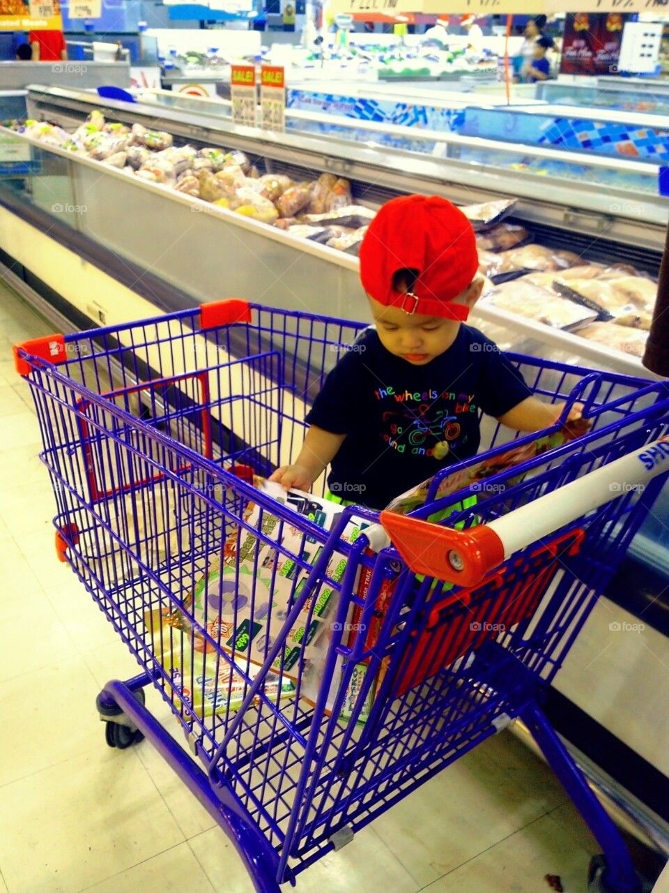 Little boy plays inside a grocery cart