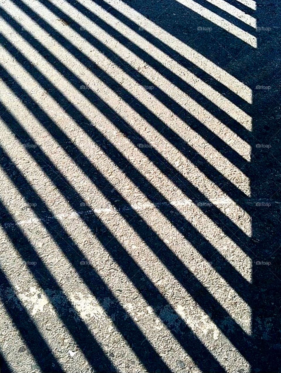 Pattern caused by shadows through a fence causing geometric lines. 