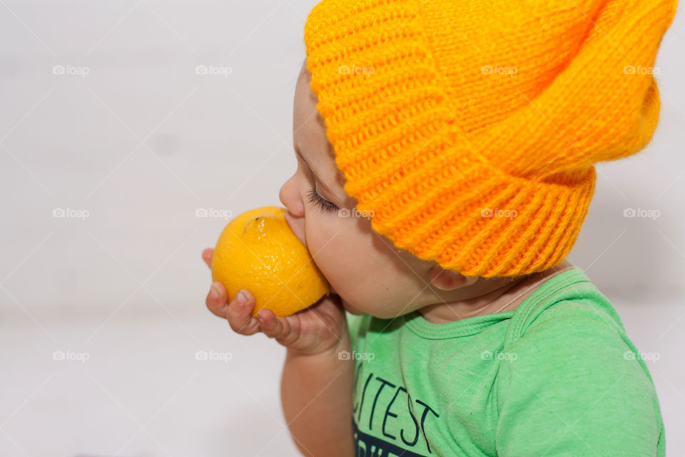 boy in yellow hat eats yellow lemon