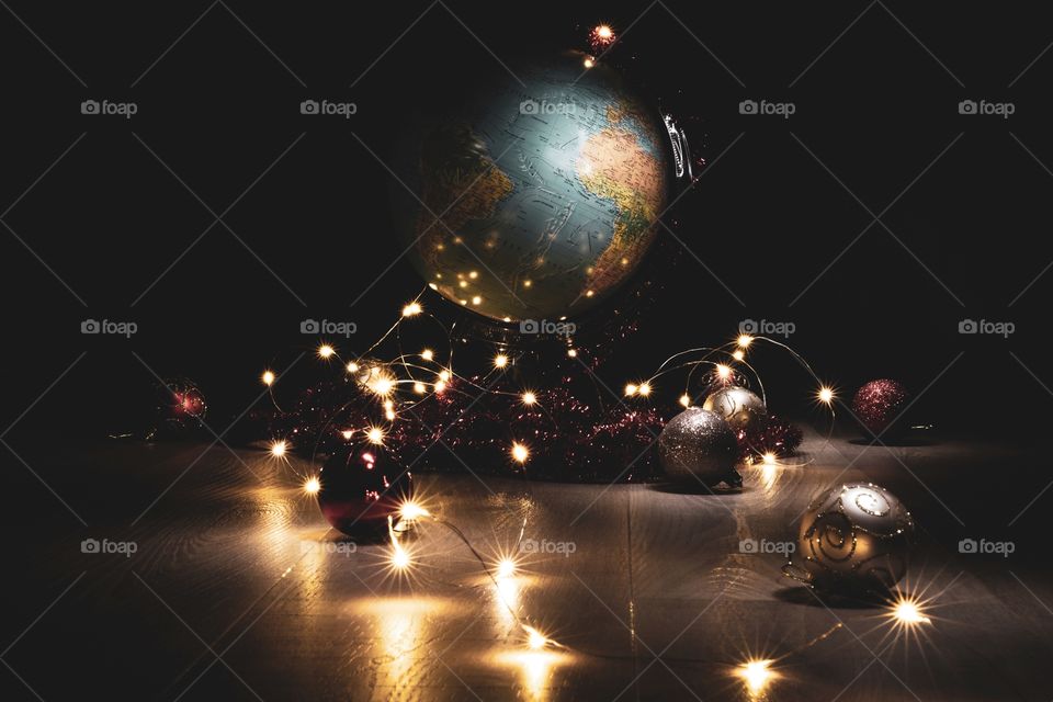 A festive portrait of a world globe with christmas decorations around it and christmas lights. depicting the world in joy in the holiday period.