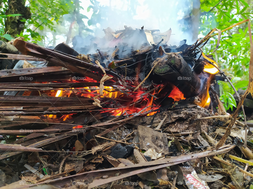 garbage and some wood that is burned and creates fire and smoke