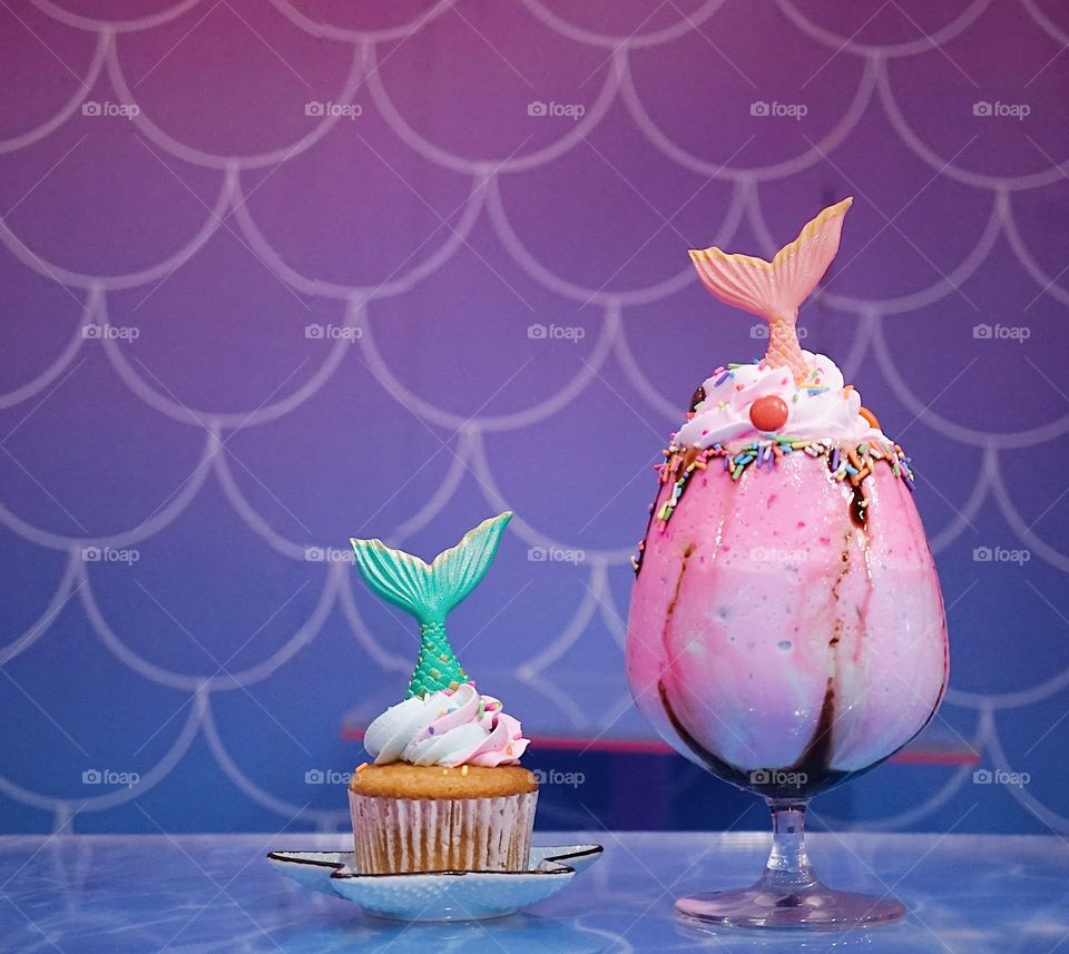 Mermaid cupcake and mermaid rainbow milkshake. With soft focus on the green fish tail in the cupcake. fairy takes and fantasy concept.