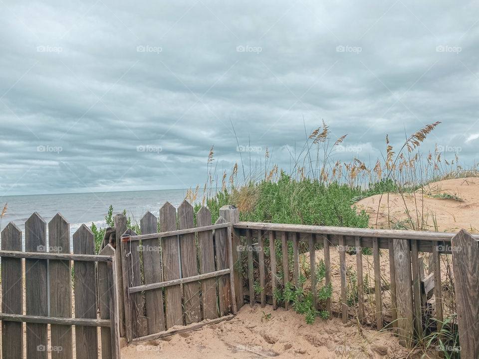 A rustic beach fence awaits a storm.