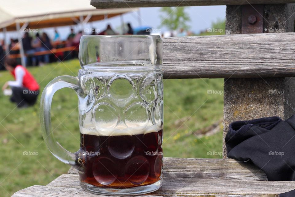A mug of dark beer stands on a bench