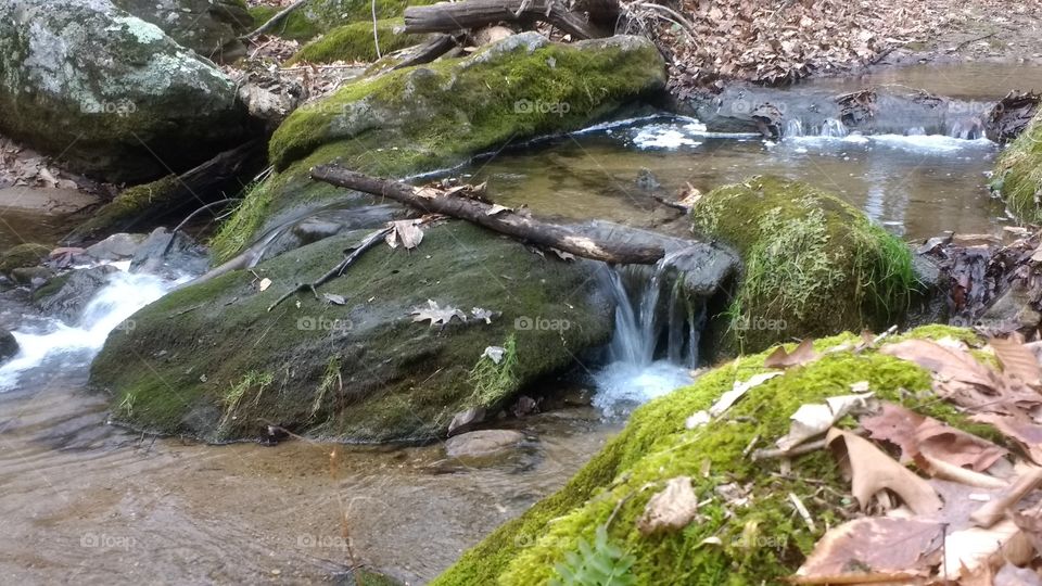 Water flow over mossy rocks  in creek