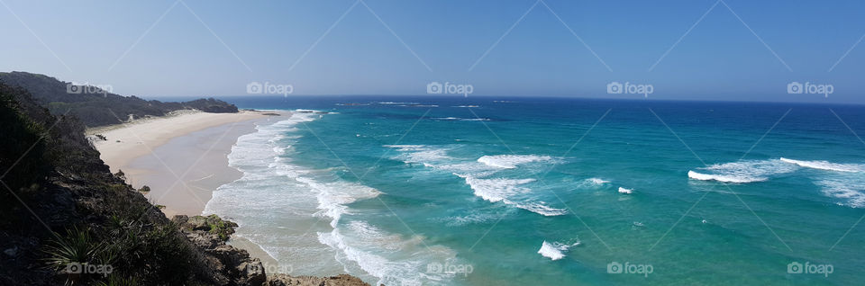 A panorama of a beautifully coloured beach with deep blues and fluorescent whites