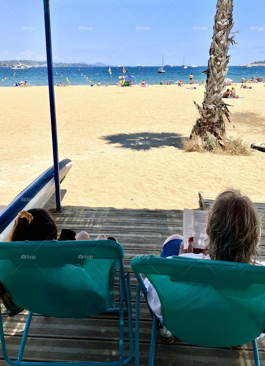 A good book in shadow in front of beach and sea : summertime 