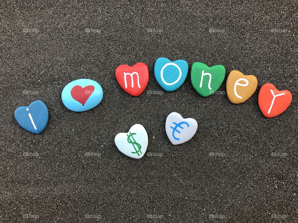 I love money, conceptual colored heart stones over black volcanic sand