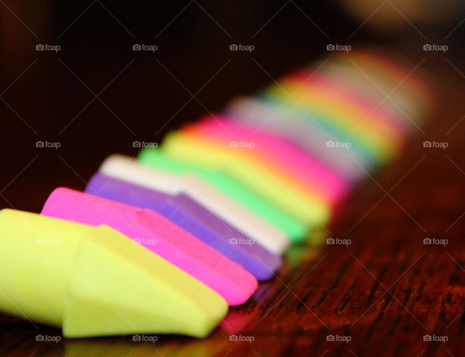 Differ colored erasers in a row on a wood table