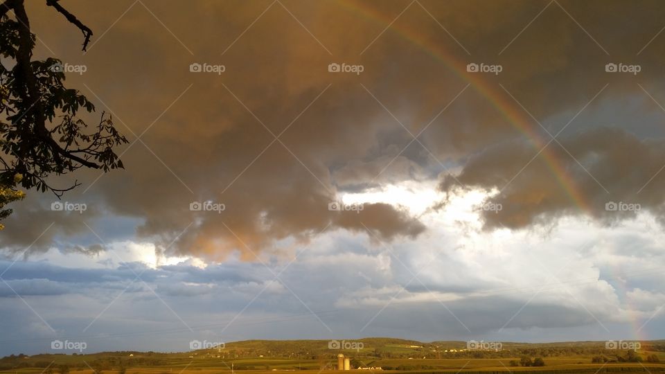 golden storms. rainbow forming at the end of the golden hour storm