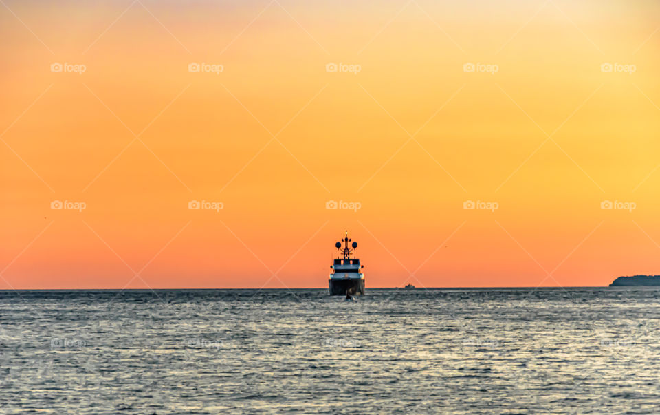 Ship sailing at sunset