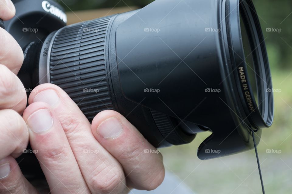 Photographer holding DSLR camera focussing closeup, male hands