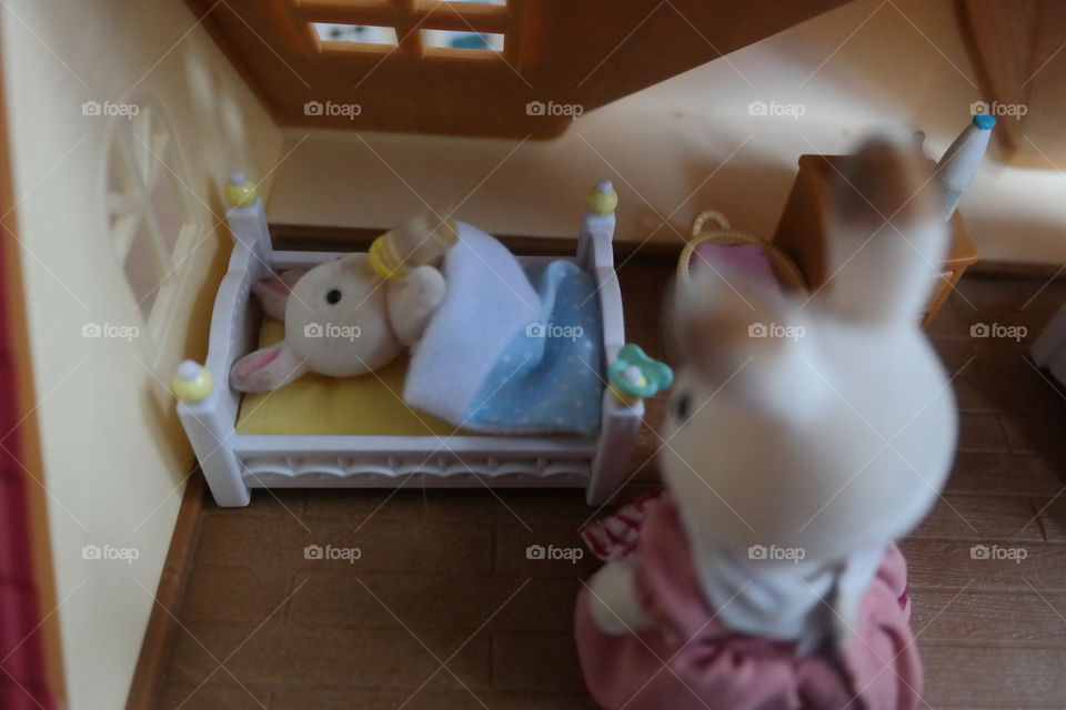 mommy bunny puts baby boy bunny to bed with a bottle in his cozy crib and fuzzy blue blanket