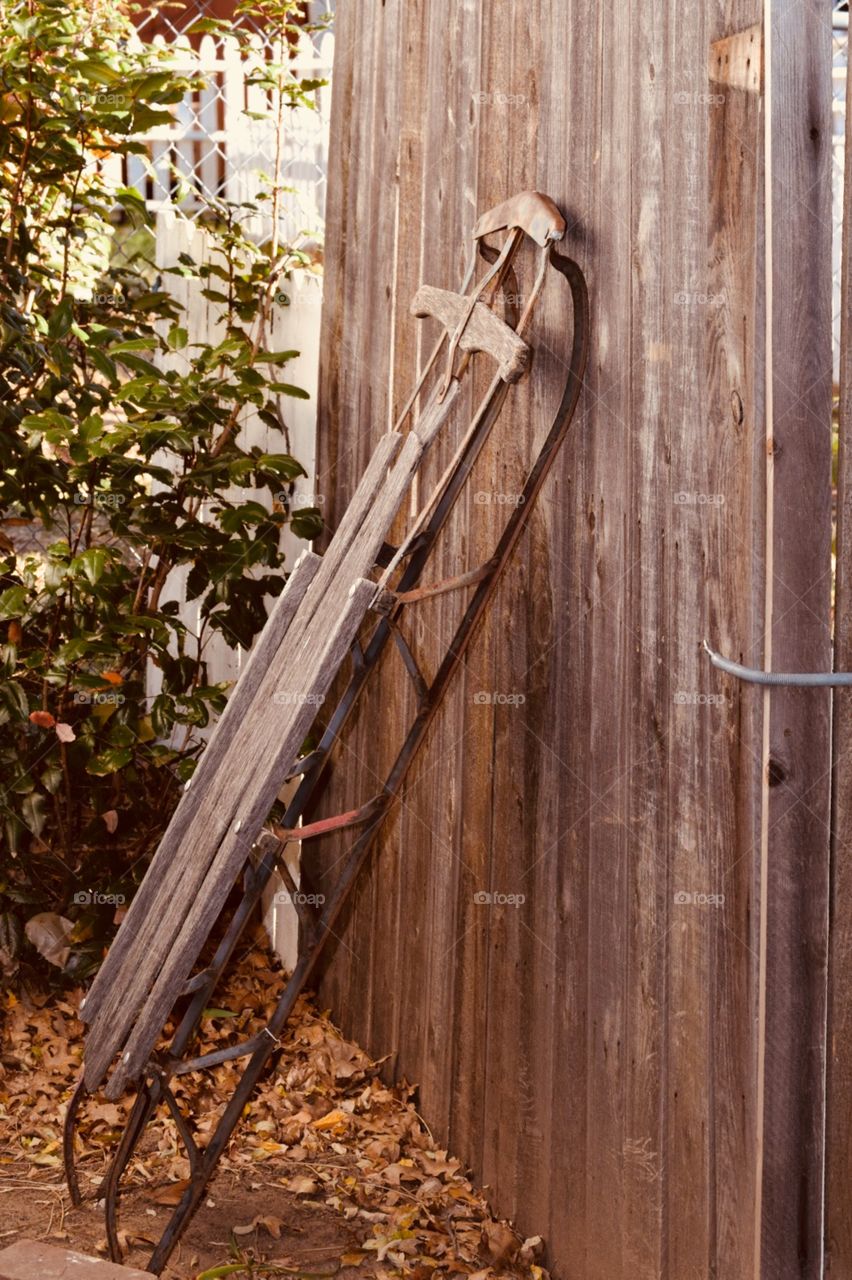 Vintage sled leaning on wooden wall