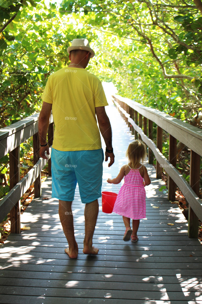 father and daughter walking to the beach