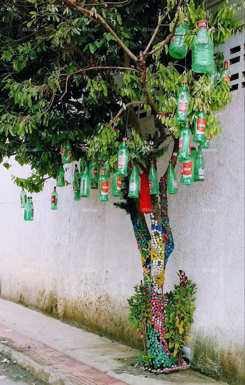árvore ornamentada com tampinhas e garrafas penduradas