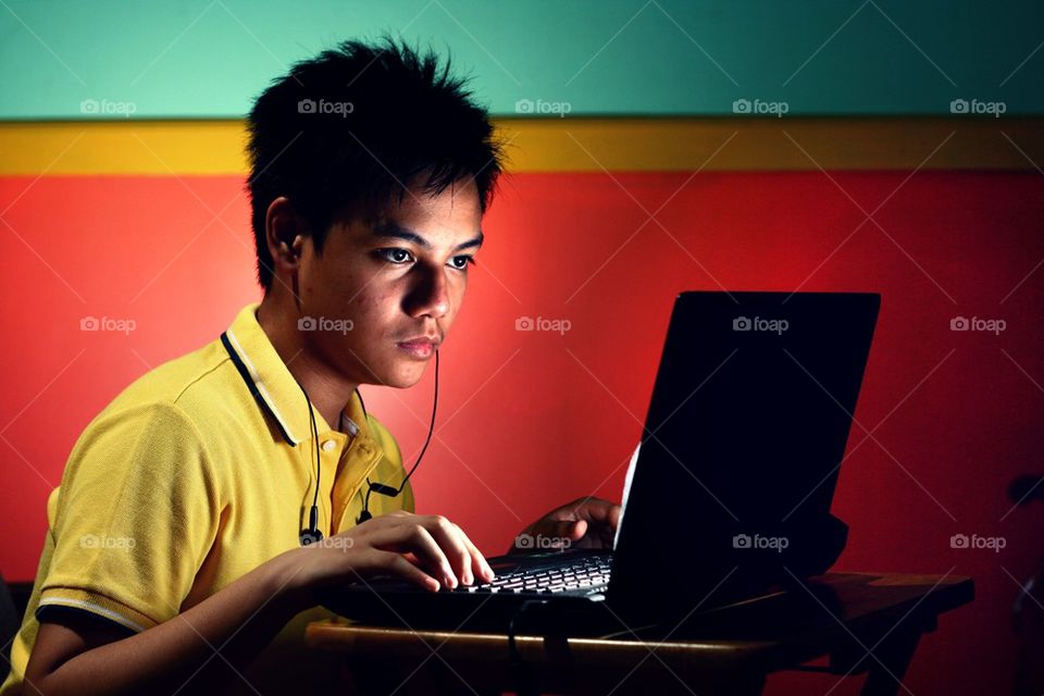 young asian teen working on a laptop computer